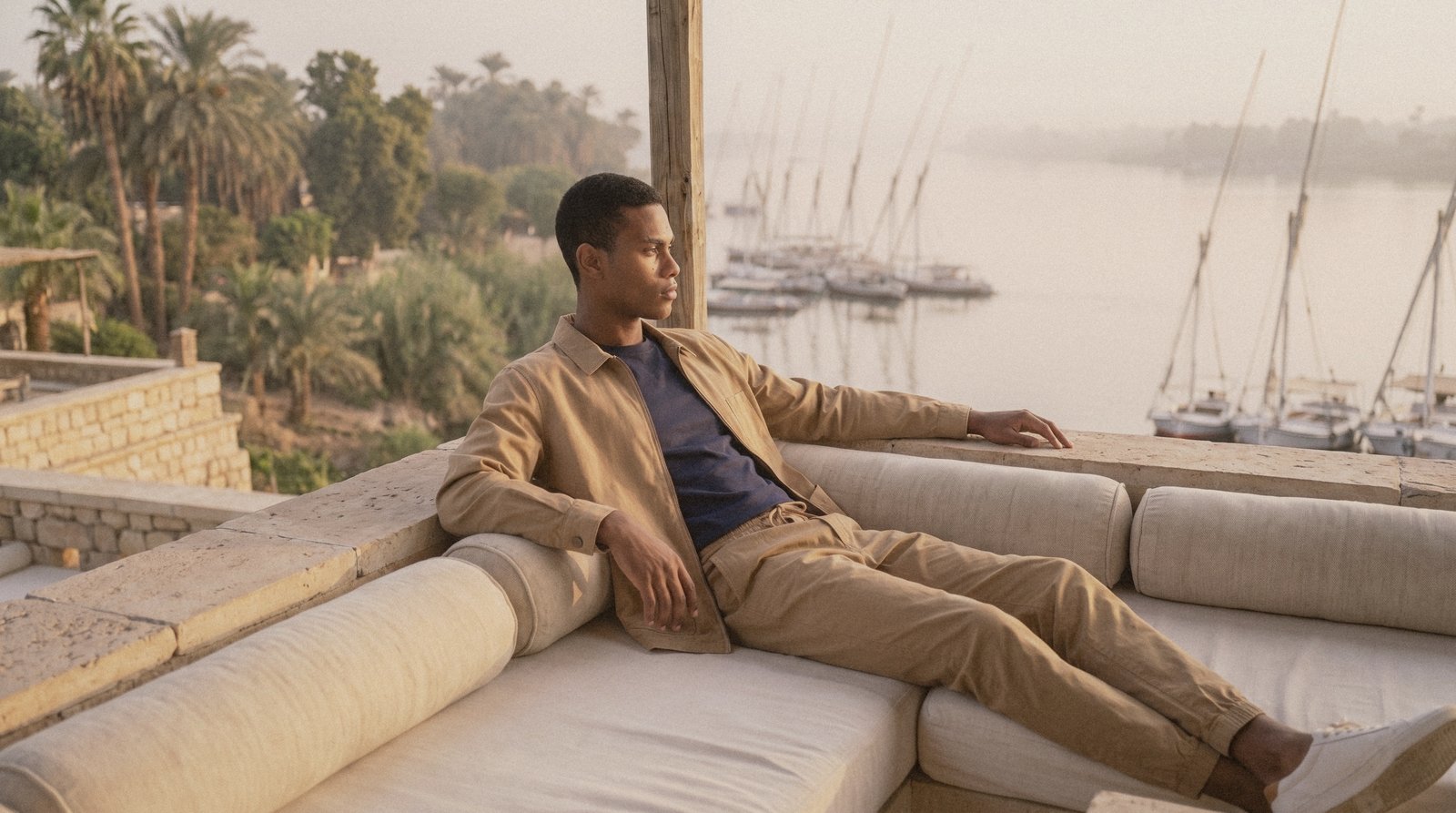 A model in a Hajjo shirt and trousers resting on a daybed in warm afternoon light